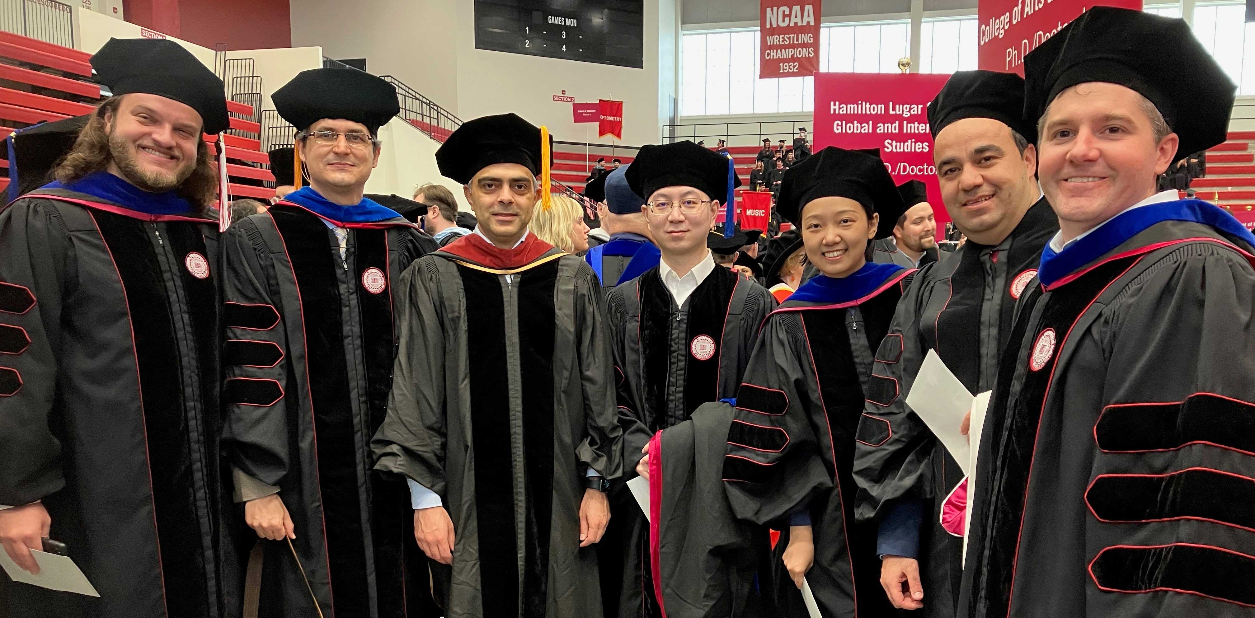 A group of people pose in Assembly Hall, dressed in doctoral caps and gowns.