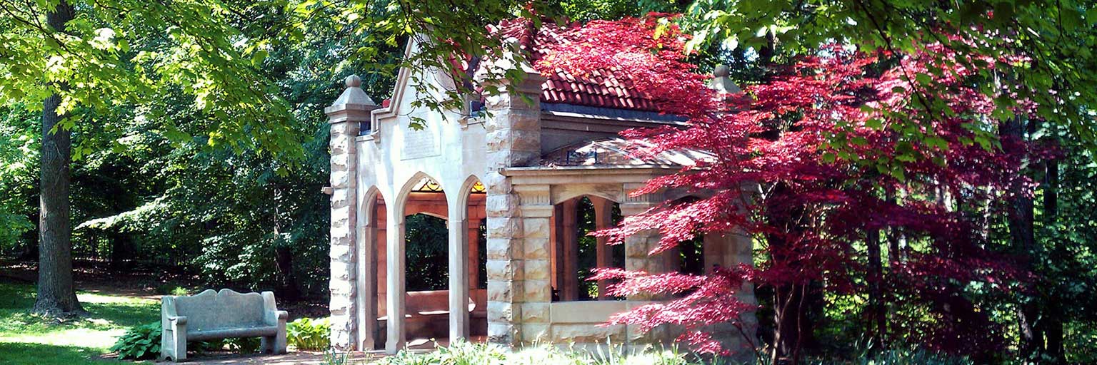 The Well House in spring, with flowering pink trees surrounding it.