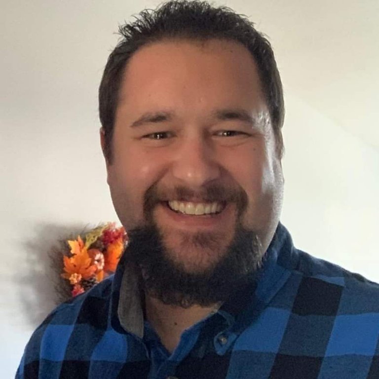 A headshot of Chris Klein, who wears a blue checkered shirt.