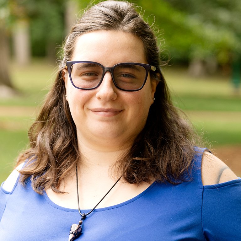 Nadine Williams, Graduate Coordinator, who wears a blue shirt and poses outside.