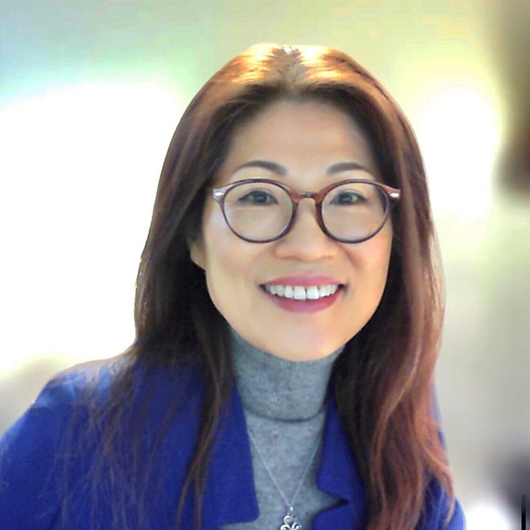 A headshot of Yoosoon Chang, who wears a blue suit and poses outside.